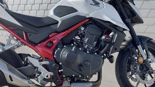 Honda CB750 Hornet met man die tegen een gebouw leunt.