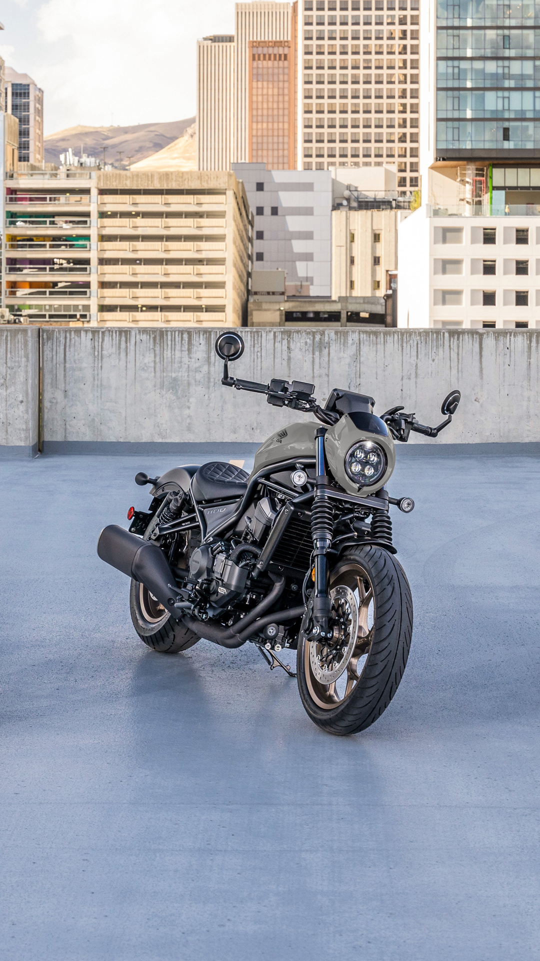Een CMX1100 motorfiets buiten, voor een modern gebouw.