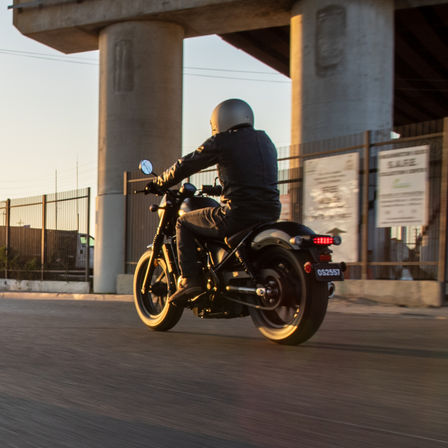 Driekwart achteraanzicht van Honda CMX500 Rebel, rijdend in een straat.