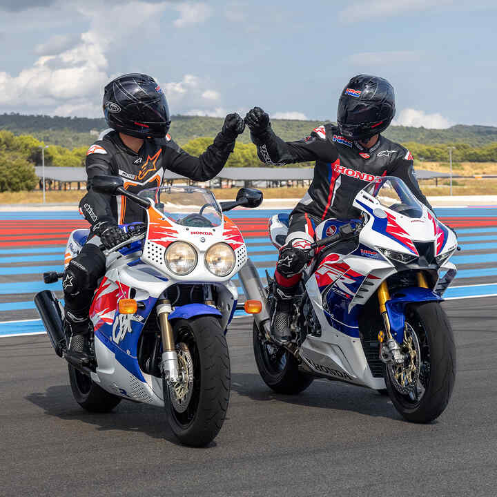 Vooraanzicht van twee fistbumpende rijders op Honda Fireblades op het circuit.