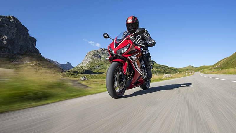CBR650R, driekwart linkervooraanzicht, met motorrijder op bergweg