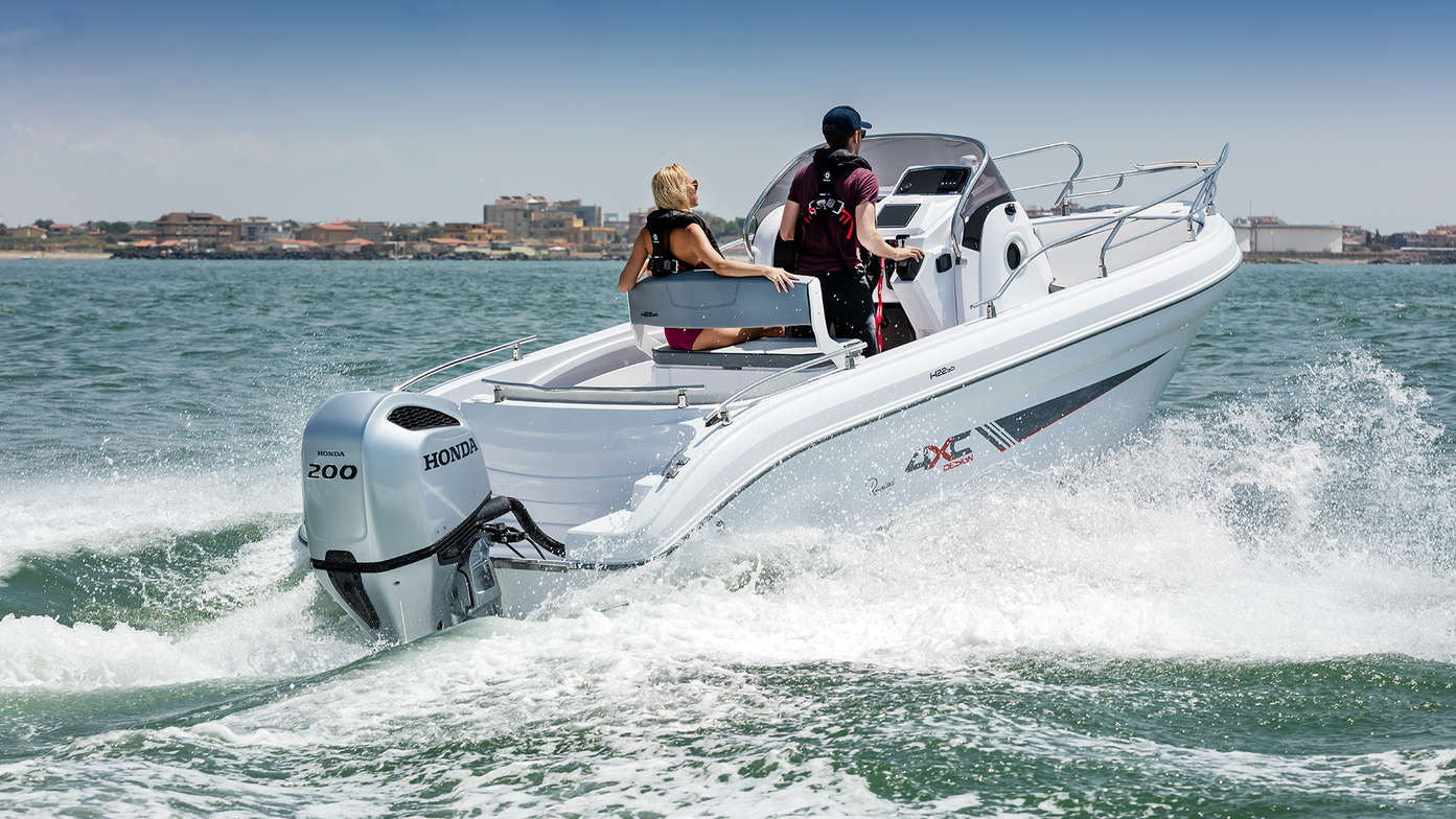 rear angled view of man steering ranieri boat with a woman, with honda outboard engine